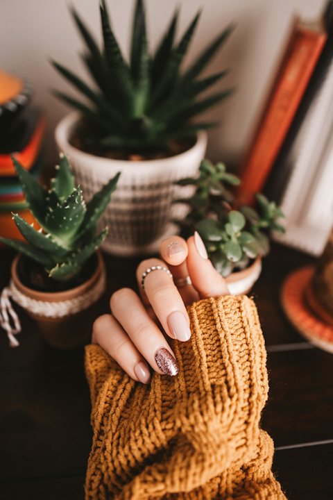 Cozy fall nails with an orange knit sweater and plants