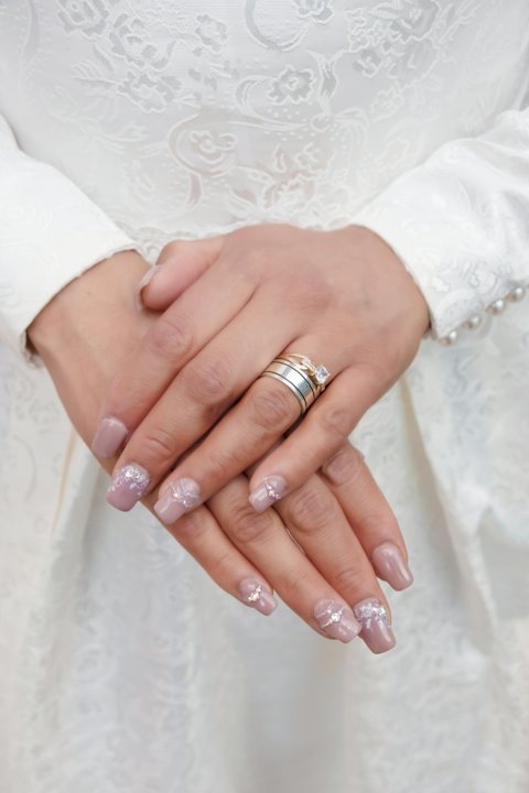 Bridal nails with an engagement ring on a white dress