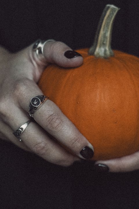 Dark Halloween nails holding a small pumpkin