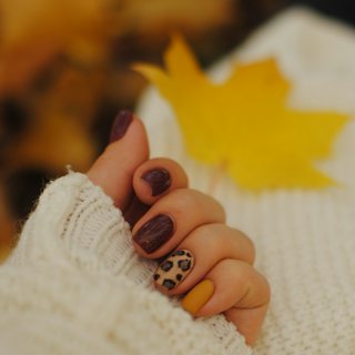 Fall manicure with a cozy cream sweater and an autumn leaf